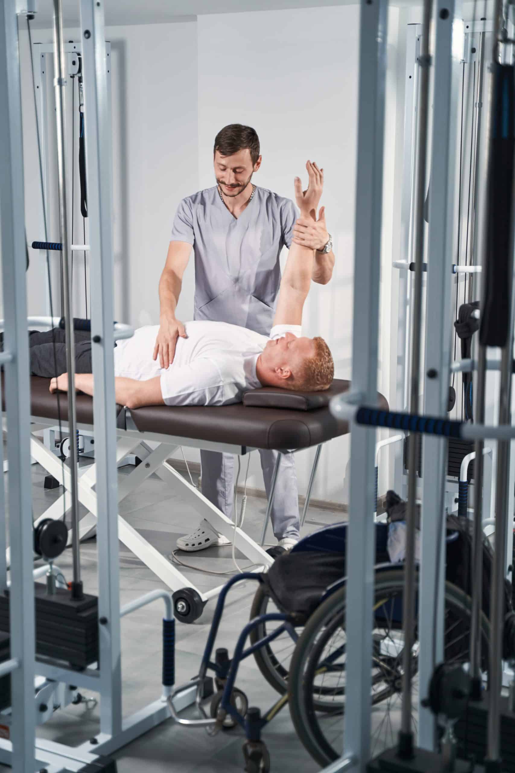 Young physioterapist man make arm rehab treatment to male patient