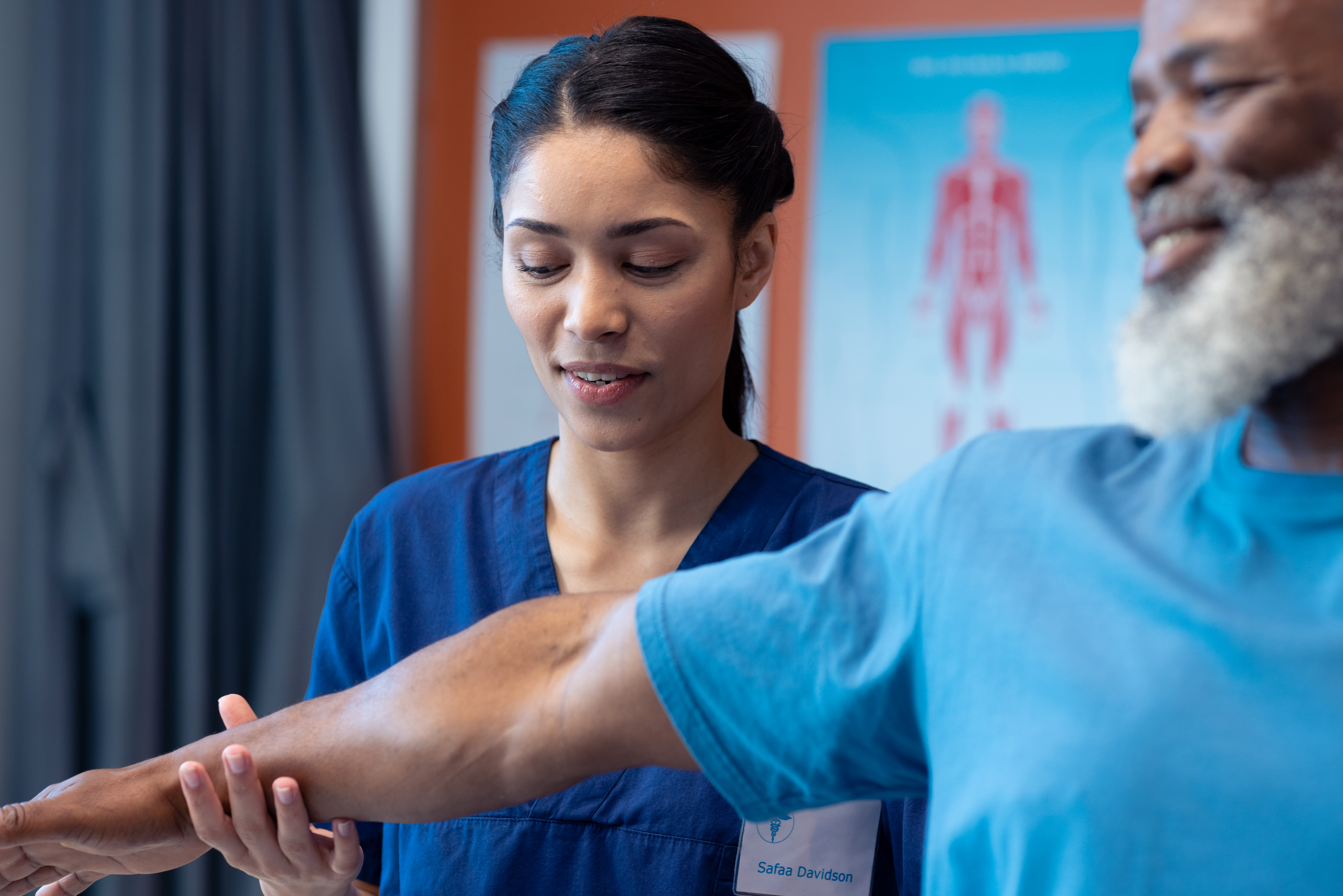 Diverse female physiotherapist treating arm of senior male patient, copy space. Hospital, medical and healthcare services.