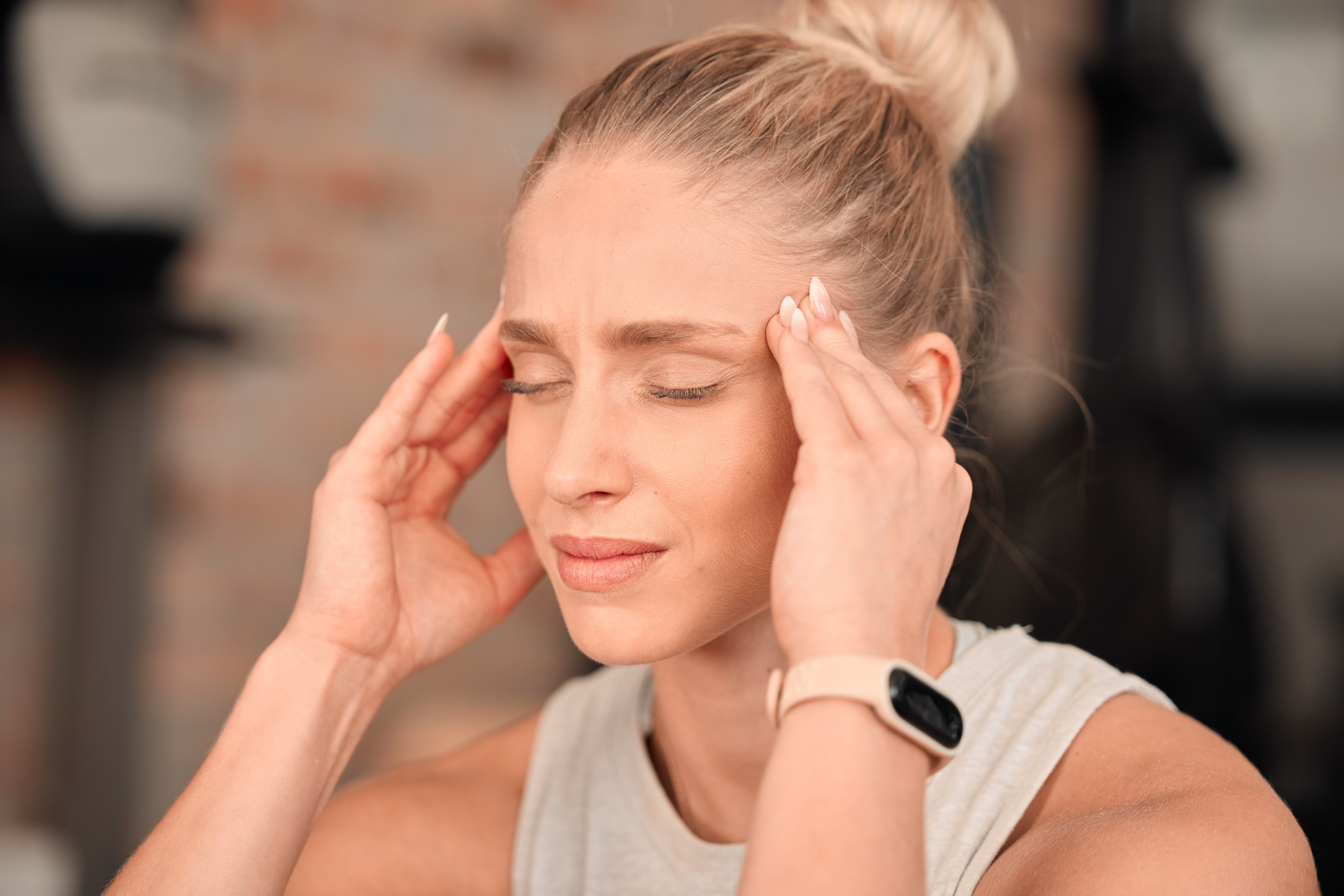 Woman, headache and pain at gym for fitness, exercise anxiety and workout challenge. Face of female.