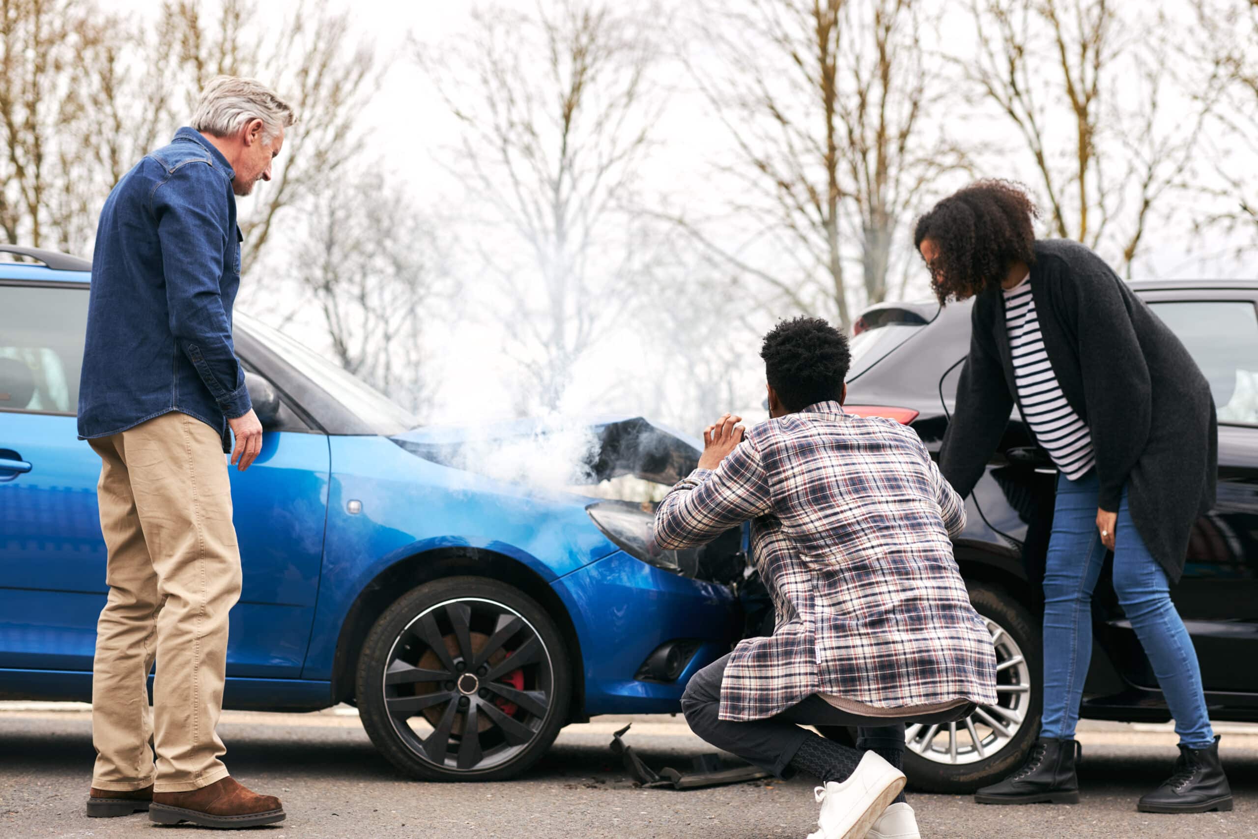 Young couple take photos on mobile phone of damage to car in accident with senior driver